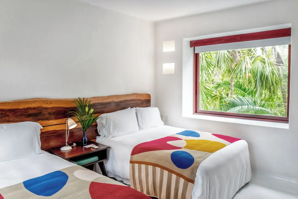 Twin beds with colorful throws and jungle view at Hotel Esencia