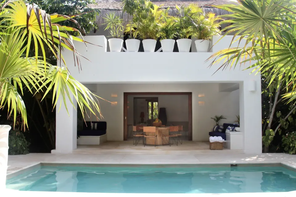 Pool and open-air dining pavilion framed by tropical plants at Hotel Esencia