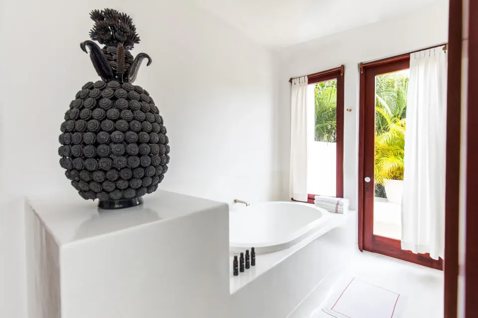 Sculptural decorative object beside the bathtub and patio door at Hotel Esencia
