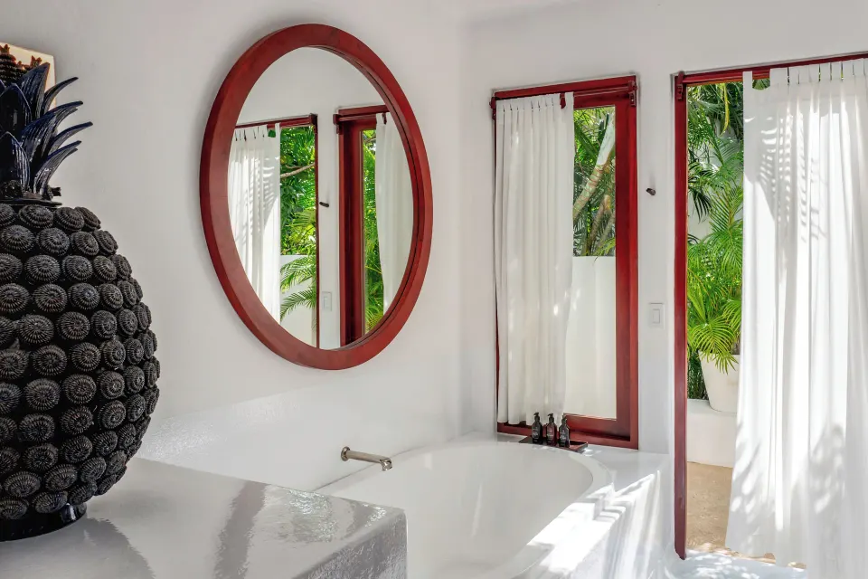 Freestanding bathtub with round mirror and garden view at Hotel Esencia