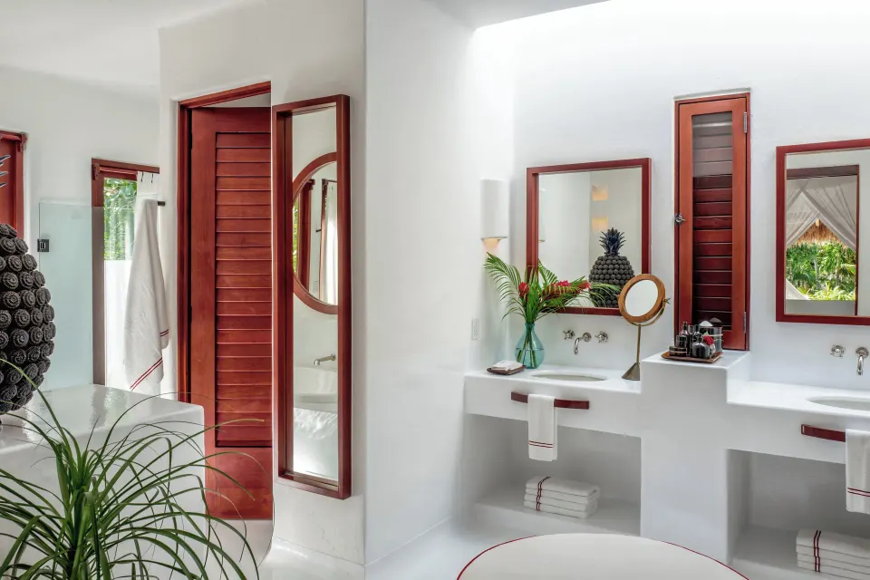 Bright white villa bathroom double vanity and wooden shutters at Hotel Esencia