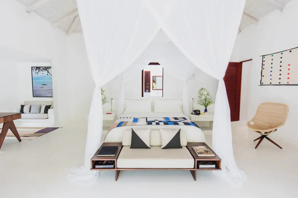 Canopied king bed in a bright white villa room at Hotel Esencia