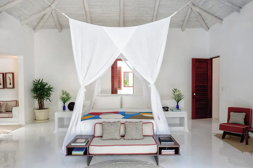 White villa bedroom with four-poster canopy and seating at Hotel Esencia