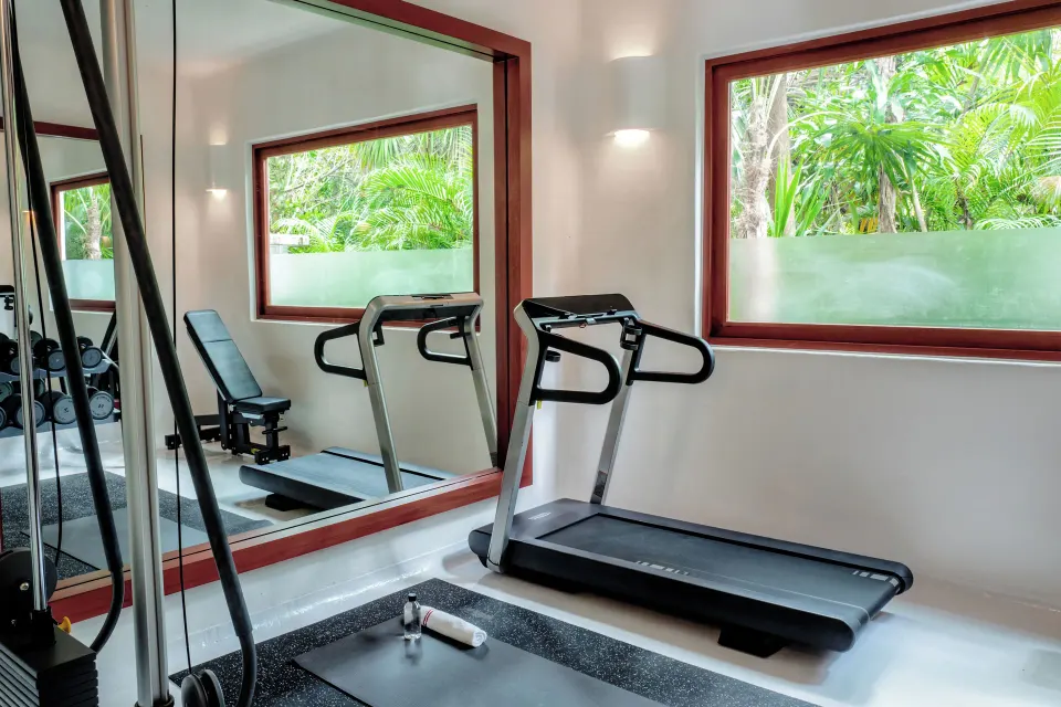 Small gym with treadmill and bench in a Villa at Hotel Esencia.