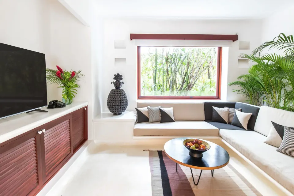 White living room seating area with TV and garden-view window at Hotel Esencia