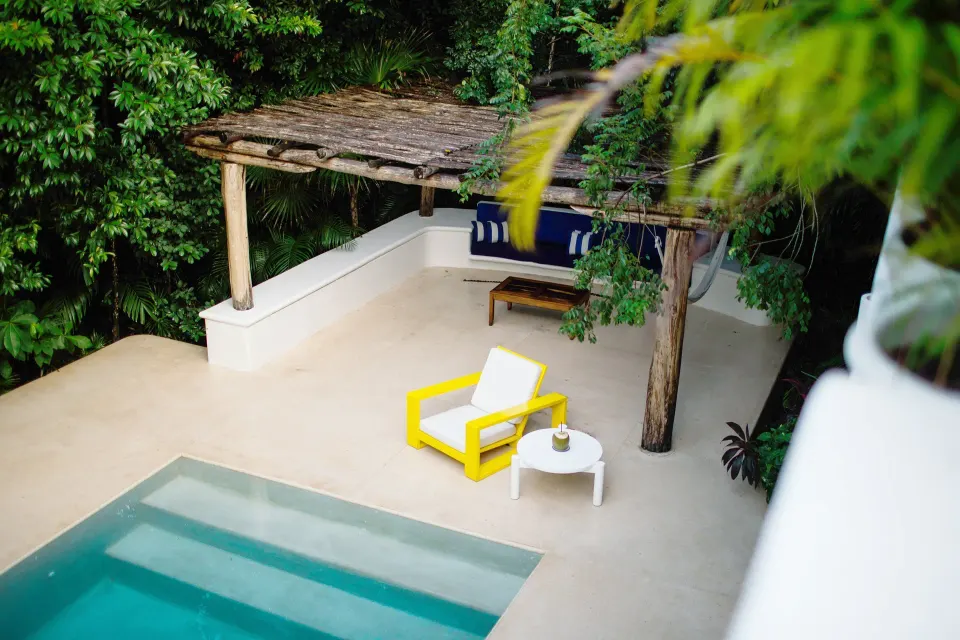 Private pool with pergola, yellow lounge chair and shaded daybed at Hotel Esencia