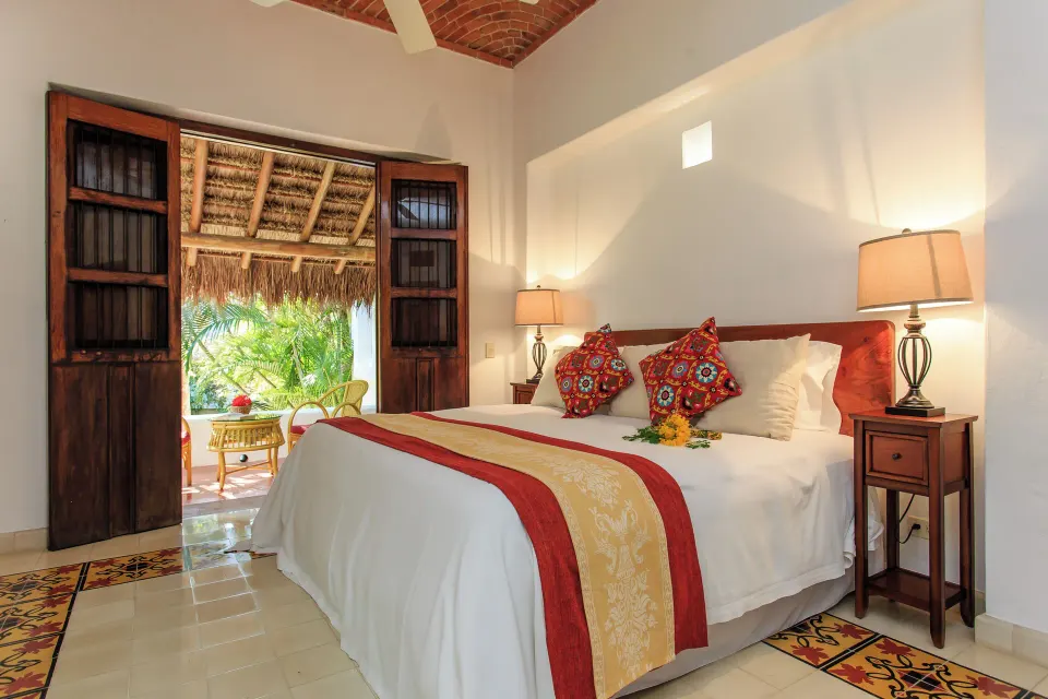 King bed with colorful cushions and open wooden doors to a terrace in Yum-Ha Private Villa at Hotel Esencia.