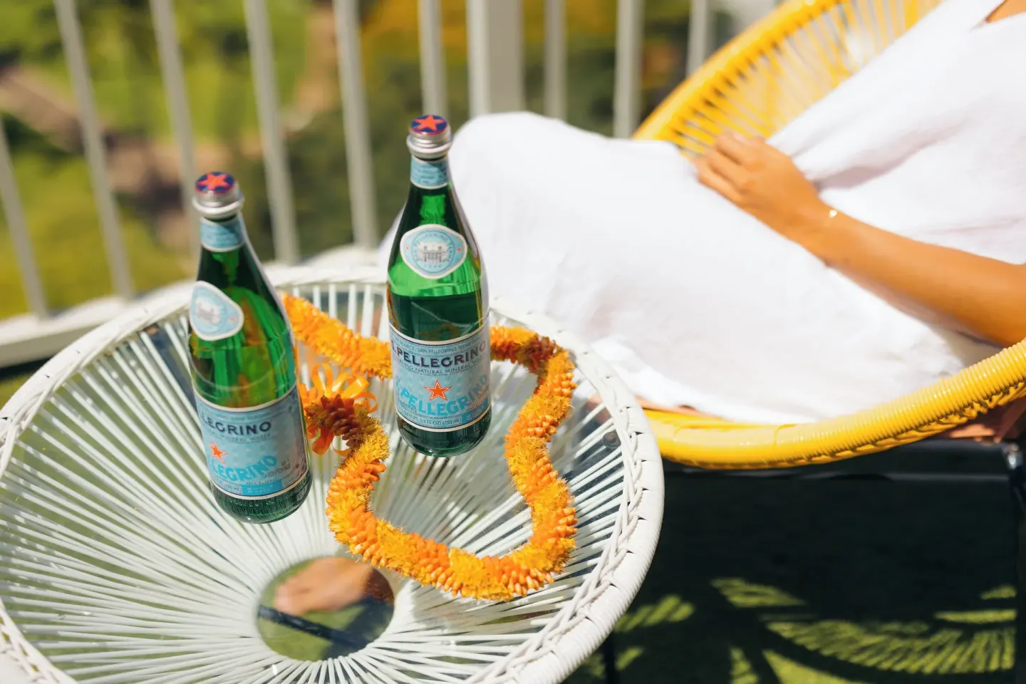 Bottled sparkling water and a lei on a balcony table at Hotel La Croix.