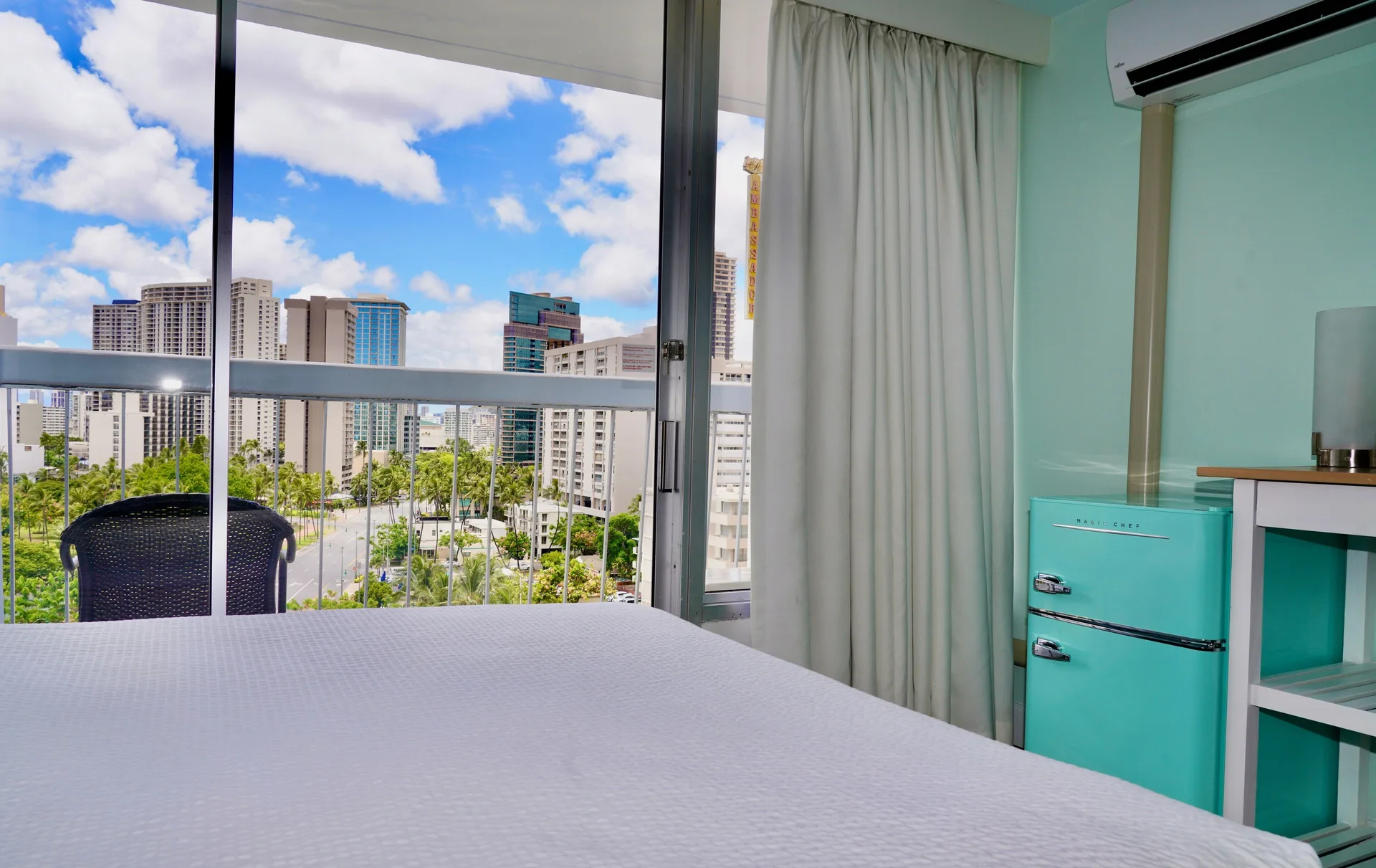 Guest room bed beside balcony doors with city view at Hotel La Croix.