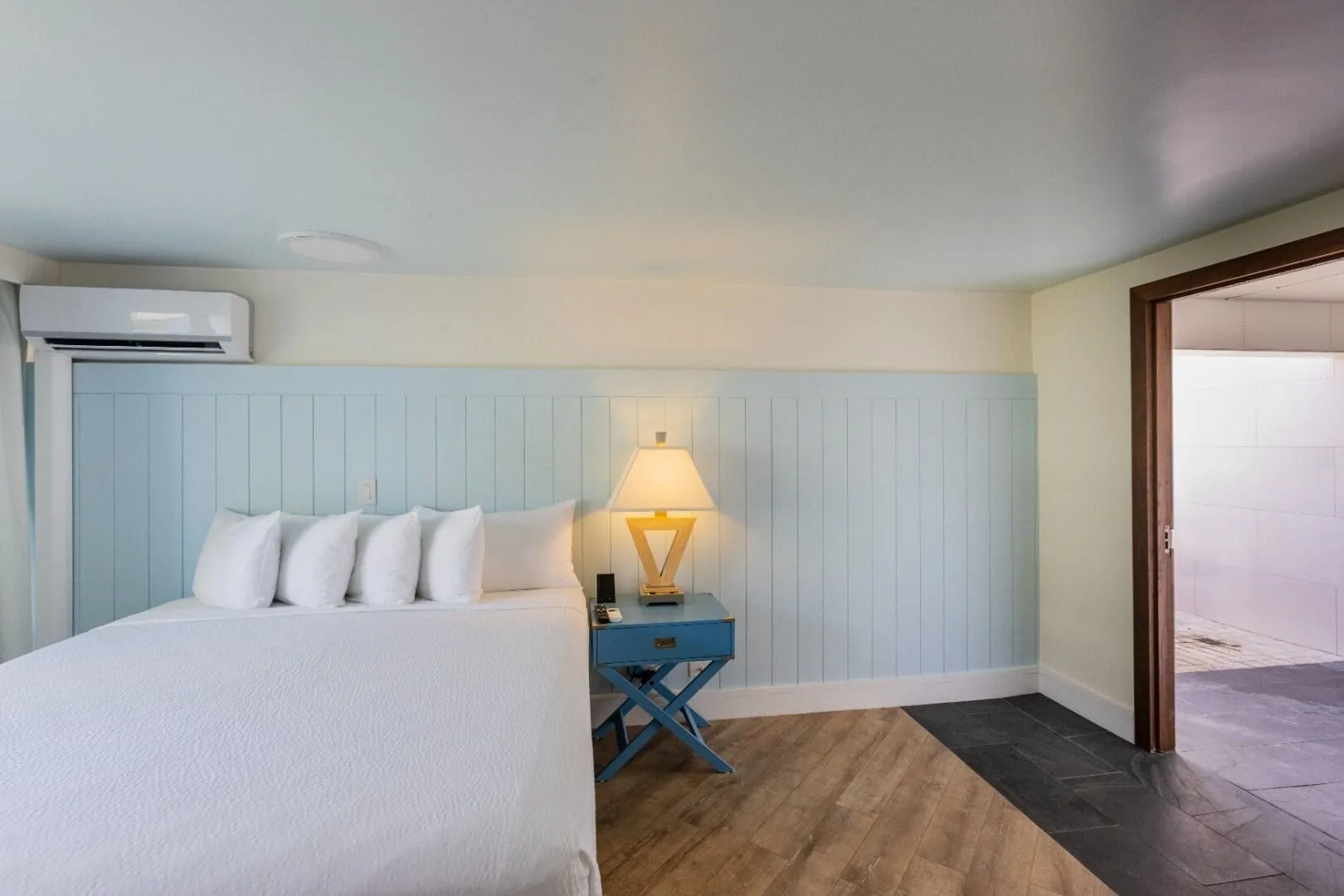 Guest room with bed, blue nightstand, and open bathroom doorway at Hotel La Croix.