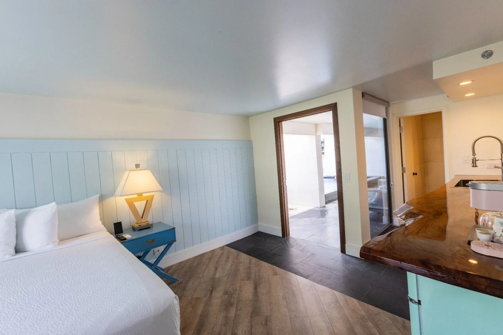 Guest room with bed, blue nightstand, wet bar, and bathroom entry at Hotel La Croix.