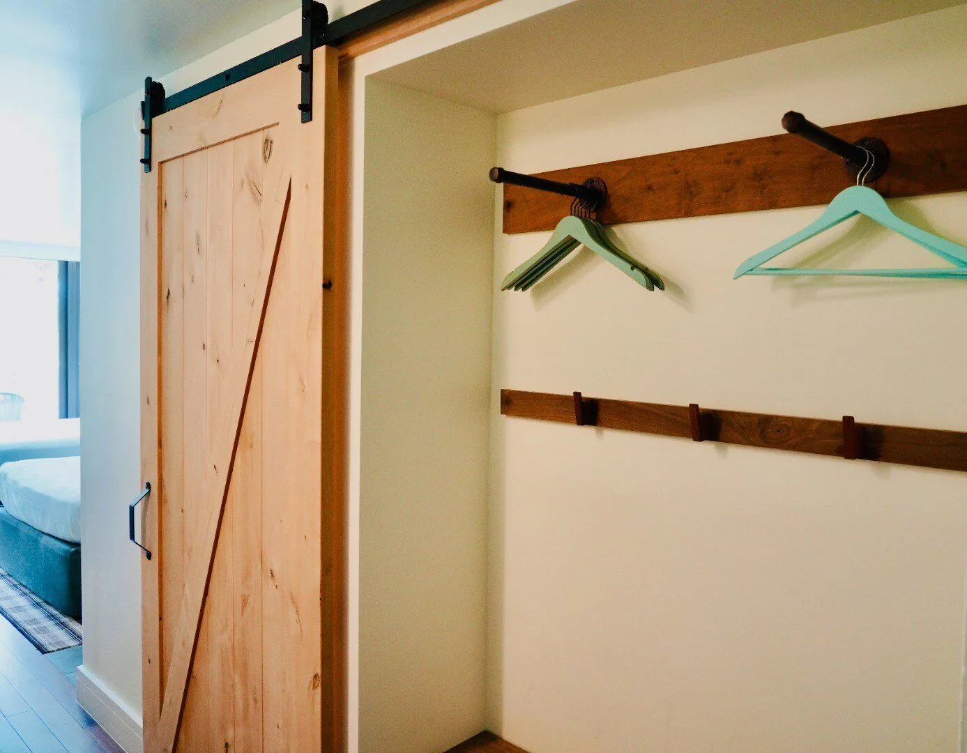 Guest room closet area at Hotel La Croix with sliding barn door, hooks, and hangers.