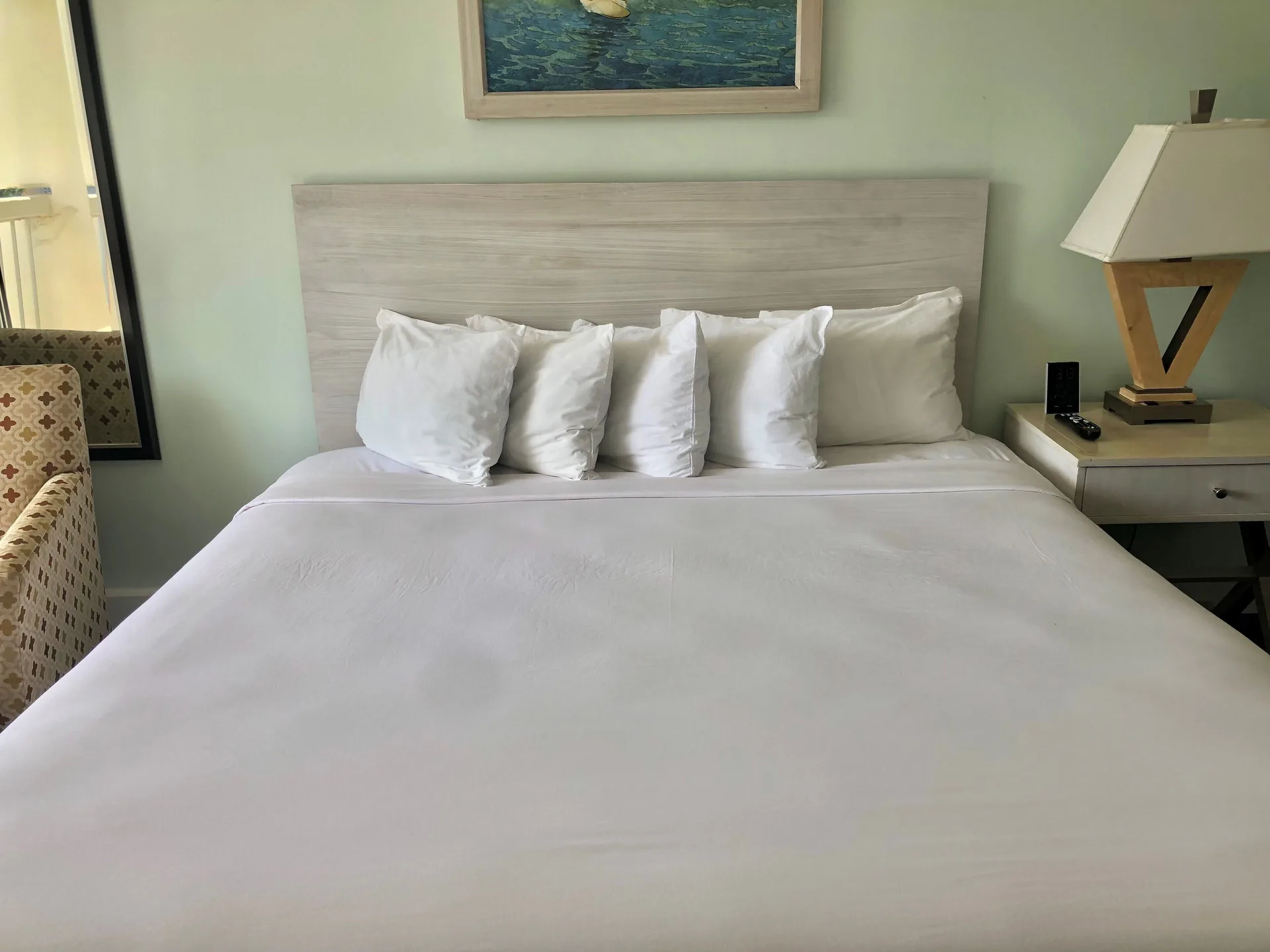 Guest room bed with white pillows and bedside lamp at Hotel La Croix.