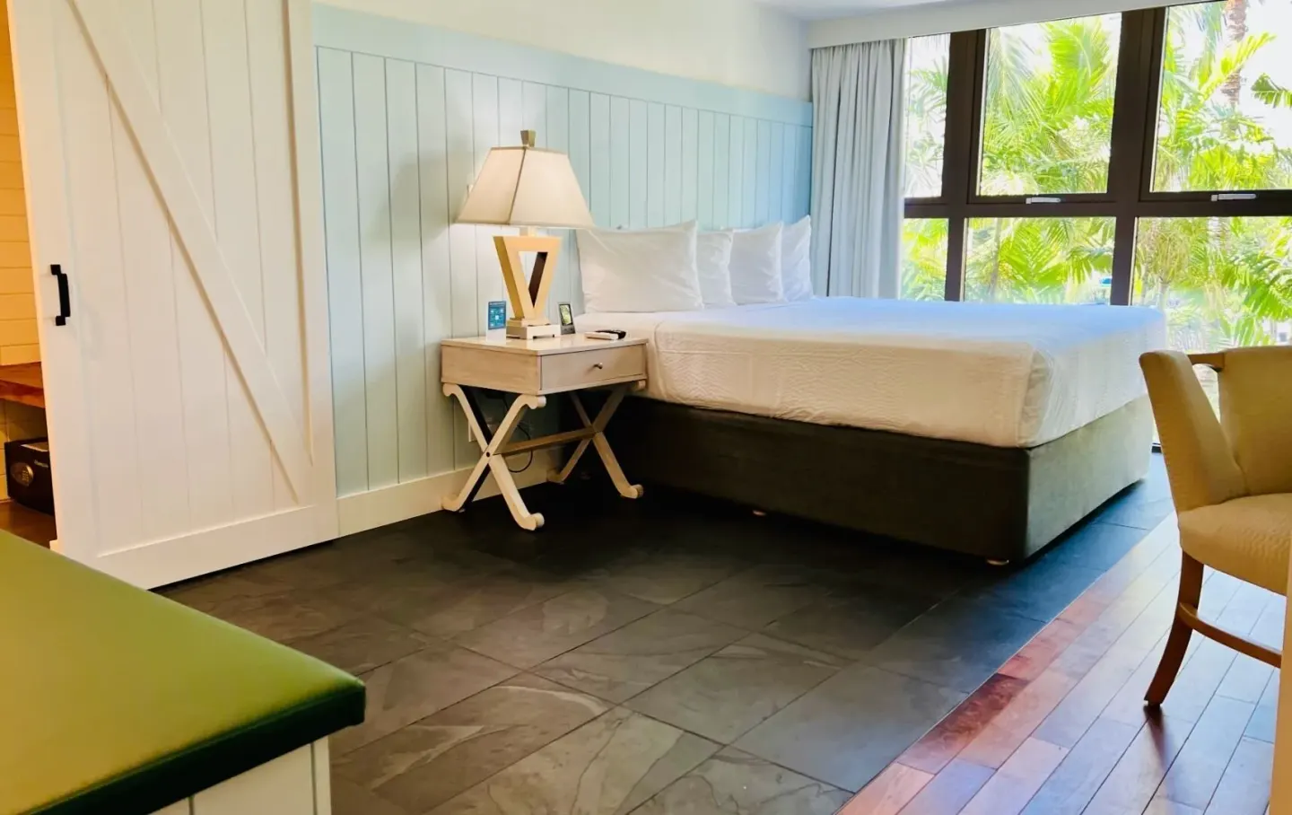 Guest room with king bed and palm-facing windows at Hotel La Croix.