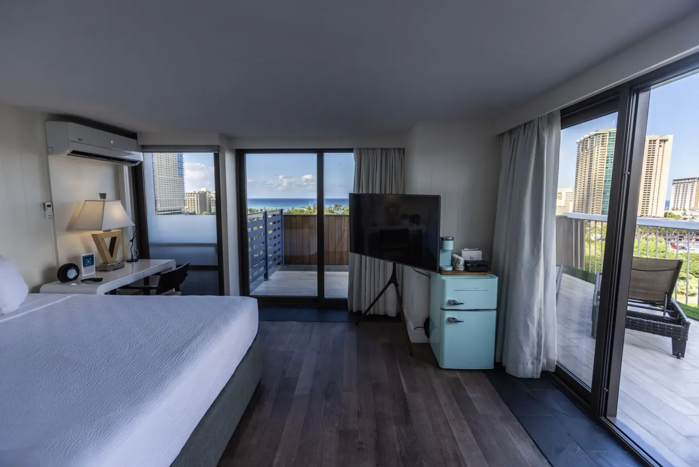 Guest room with a bed, TV, mini fridge, and two balconies at Hotel La Croix.