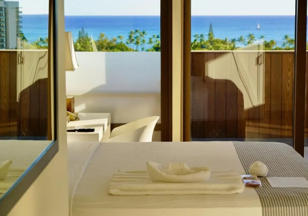 Guest room bed facing balcony doors and ocean view at Hotel La Croix.