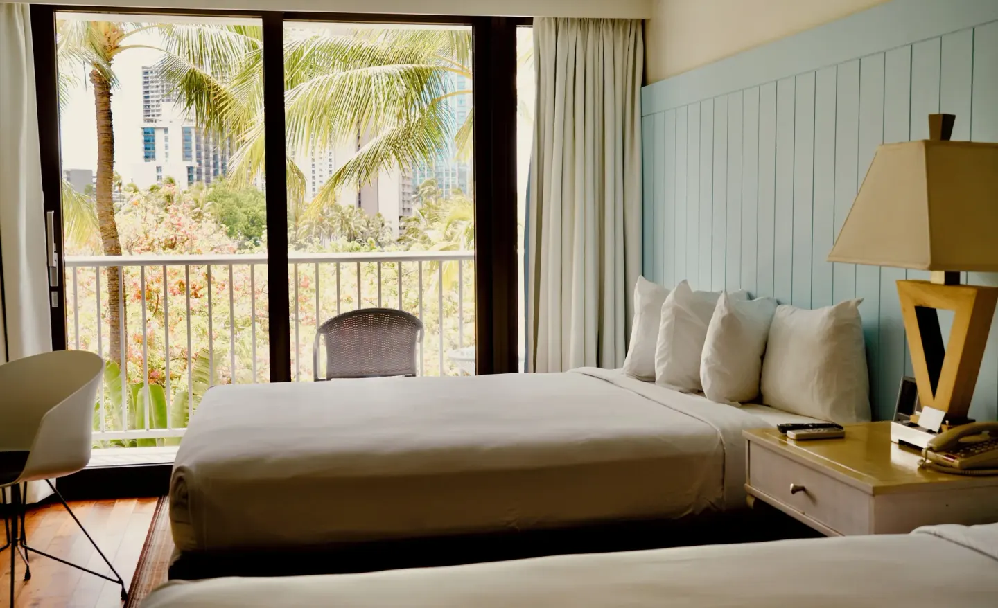 Guest room with two beds, balcony doors, and palm views at Hotel La Croix.