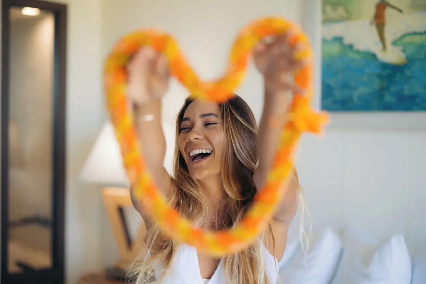 Guest holding an orange lei in a guest room at Hotel La Croix.