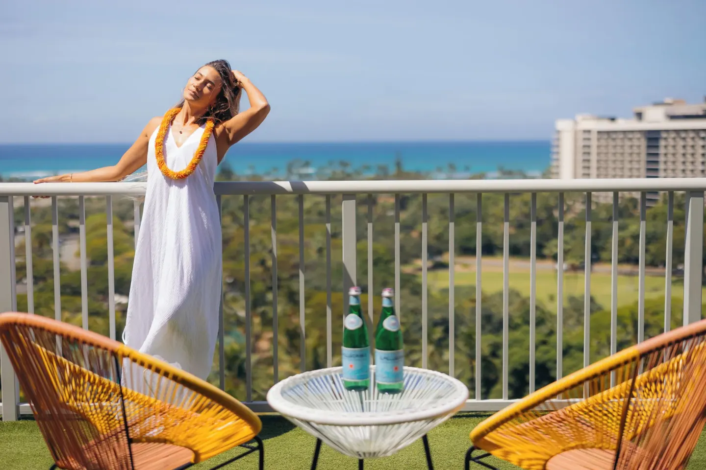 Guest on a balcony with ocean views and yellow chairs at Hotel La Croix.