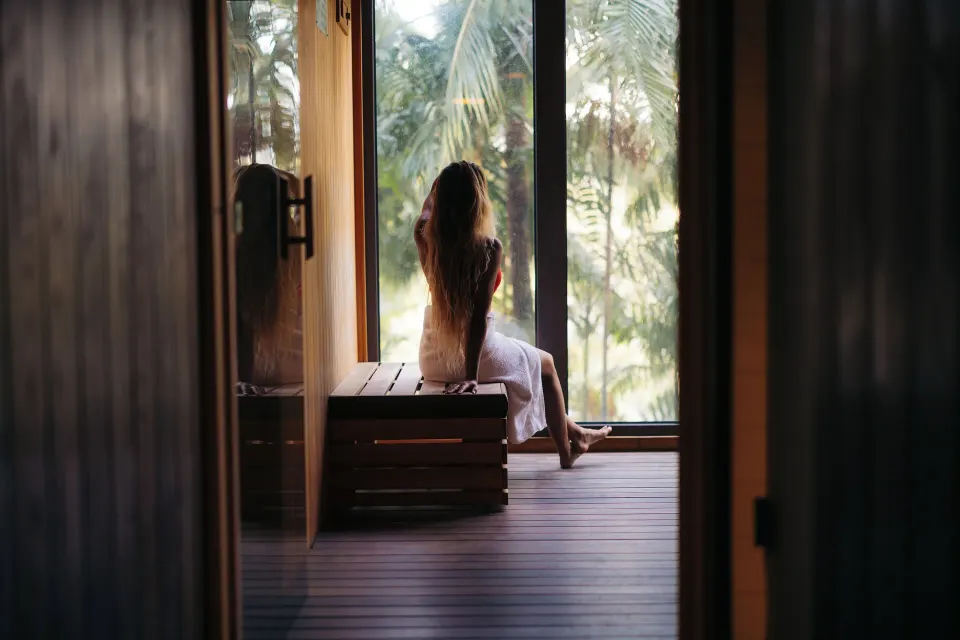 Guest in a towel sitting by tall sauna windows at Hotel La Croix.