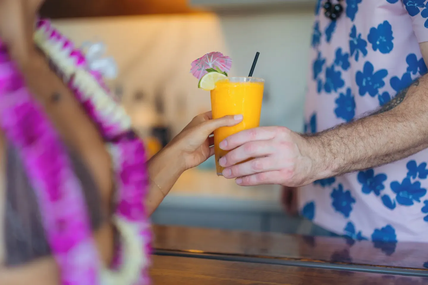 A bright orange drink being handed across a bar at Hotel La Croix.