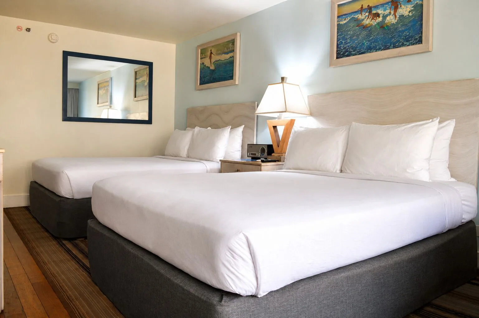 Two white beds with surf artwork in Ali'i Waikiki Two at Hotel La Croix.