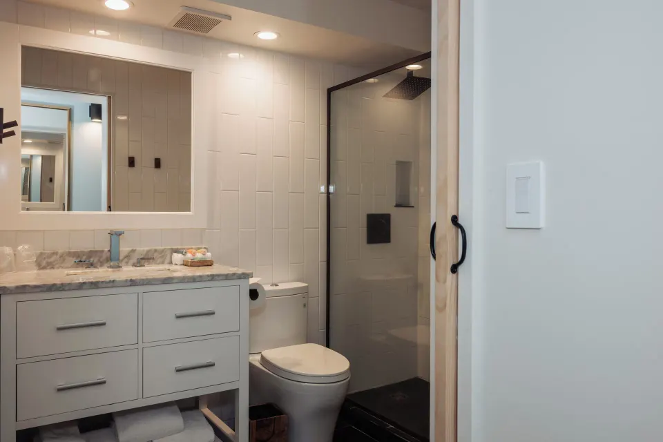 Ali'i Waikiki bathroom at Hotel La Croix with vanity, mirror, toilet, and glass-enclosed shower.