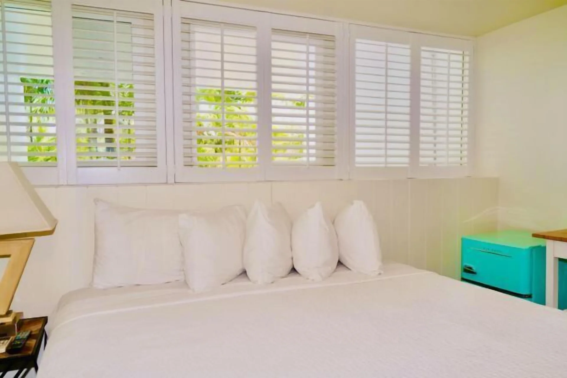 Bronze Room bed with white shutters and teal nightstand at Hotel La Croix.