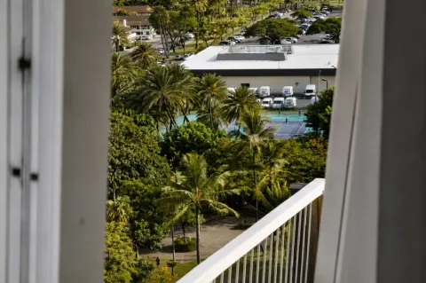 Balcony-framed view of palms and tennis courts from Hotel La Croix.