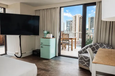 Penthouse Hoku Terrace ADA seating, TV, and balcony doors at Hotel La Croix.