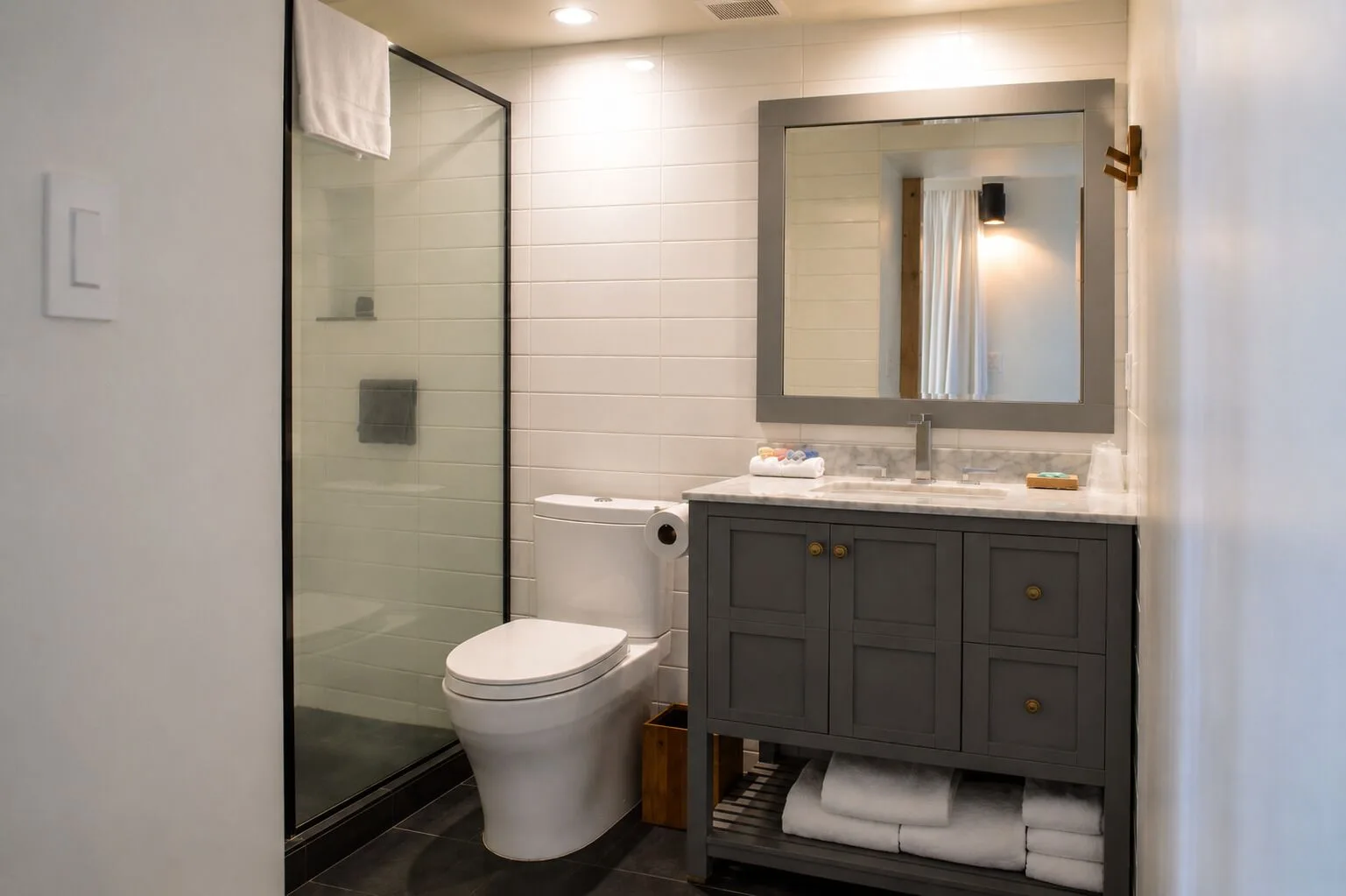 Bathroom with glass shower, vanity, and toilet in a Premium Kalakaua Haus room at Hotel La Croix.