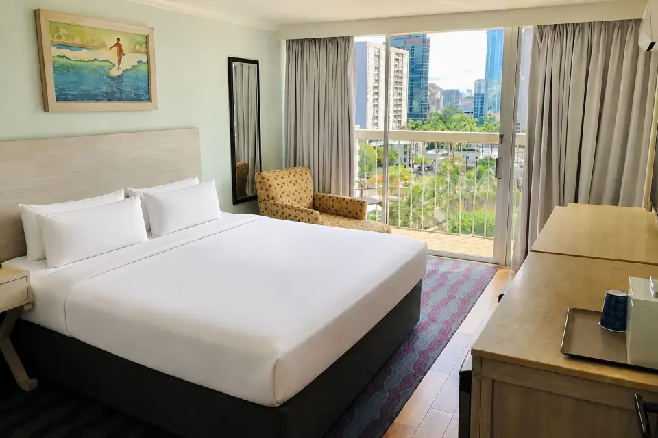 King bed and lanai doors in a Premium Kalakaua Haus Corner Two Lanai room at Hotel La Croix.