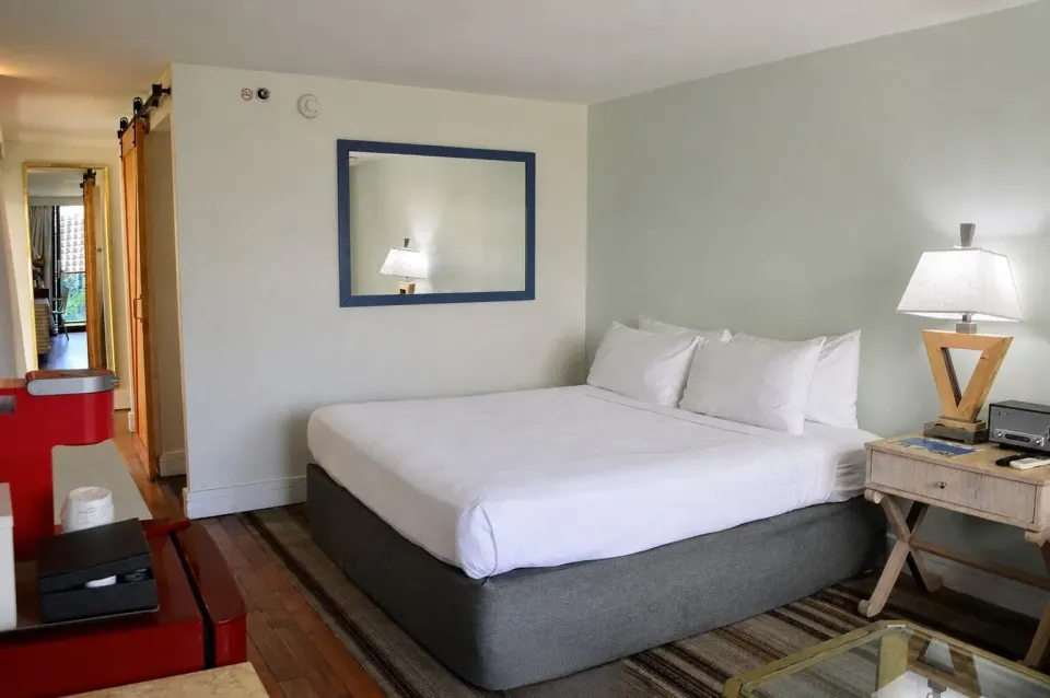 King bed and red mini fridge in a Premium Kalakaua Haus Corner Two Lanai room at Hotel La Croix.