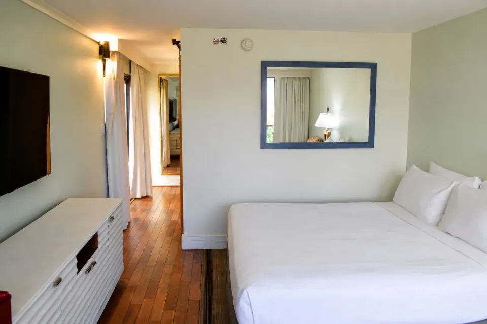 King bed, TV cabinet, and mirror in a Premium Kalakaua Haus Corner Two Lanai room at Hotel La Croix.