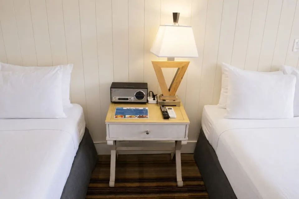 Nightstand between two beds in a Premium Kalakaua Haus room at Hotel La Croix.
