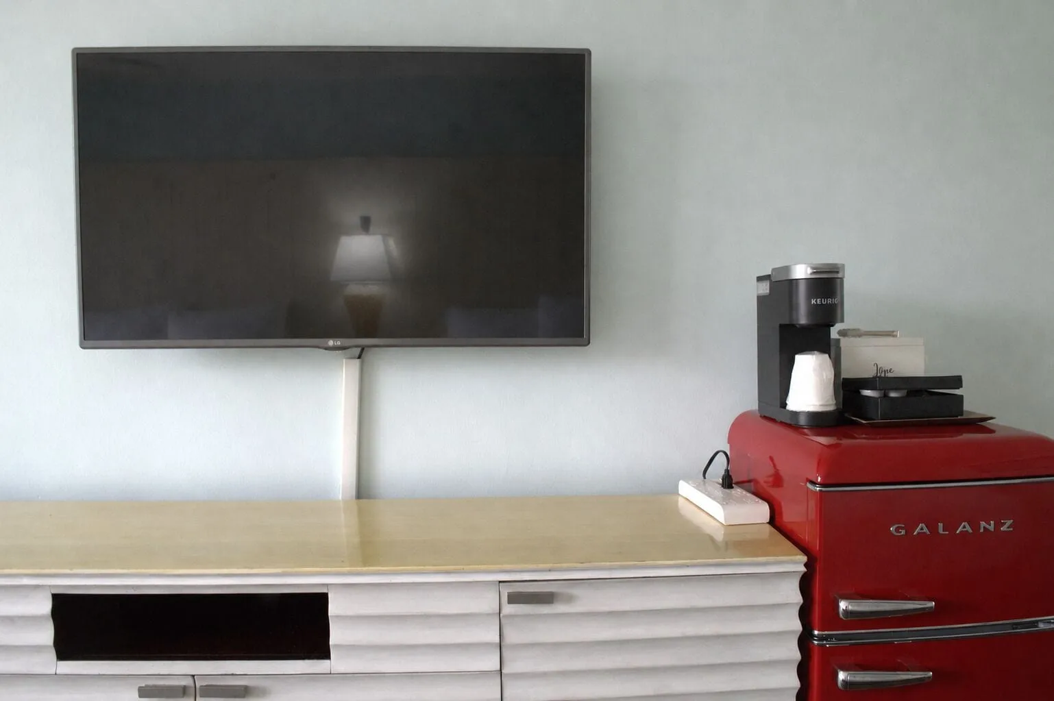 TV console, coffee maker, and red mini fridge in a Premium Kalakaua Haus room at Hotel La Croix.