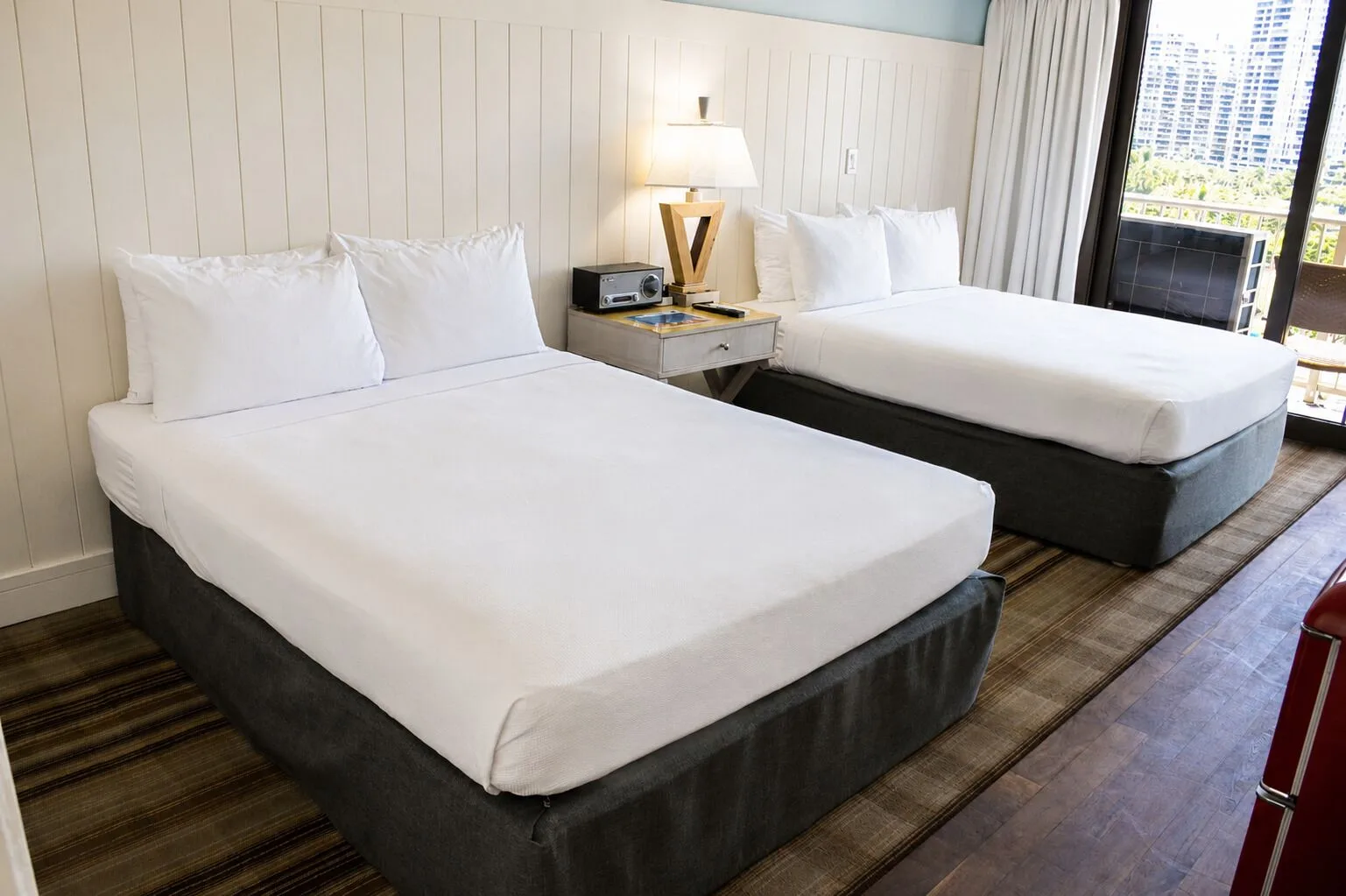 Two beds beside the lanai doors in a Premium Kalakaua Haus room at Hotel La Croix.