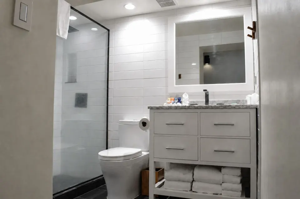Premium Kalakaua Haus bathroom with glass shower, toilet, and vanity at Hotel La Croix.