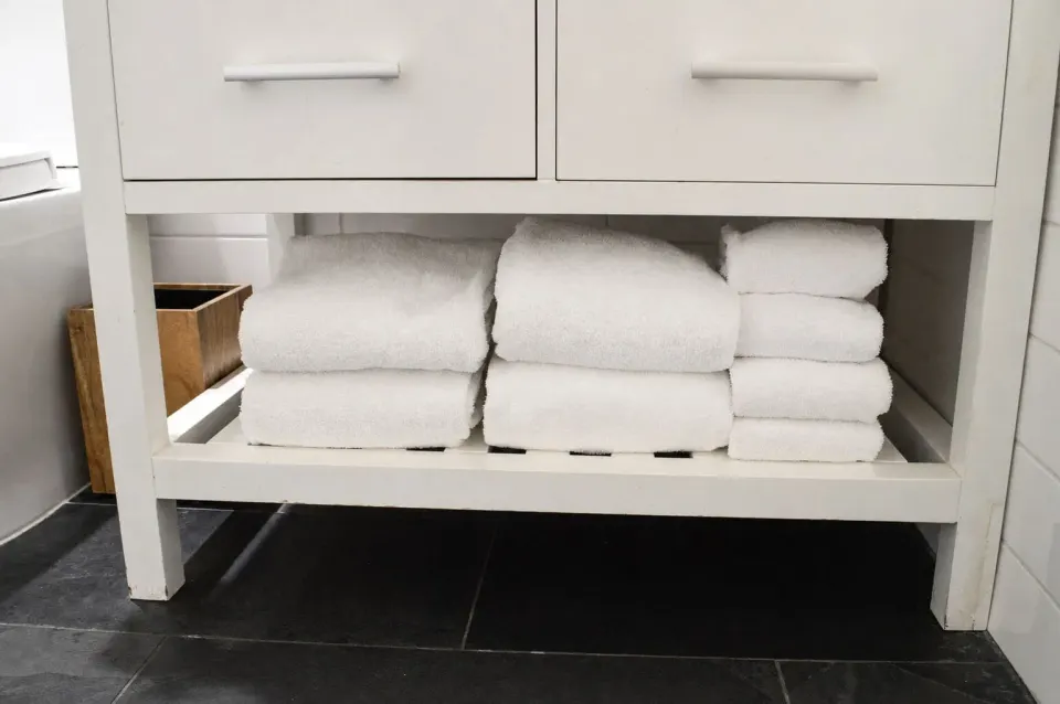 Folded white towels stored beneath the bathroom vanity at Hotel La Croix.
