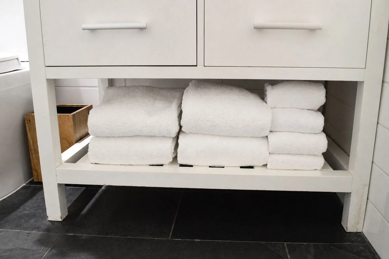 Folded white towels stored beneath the bathroom vanity at Hotel La Croix.
