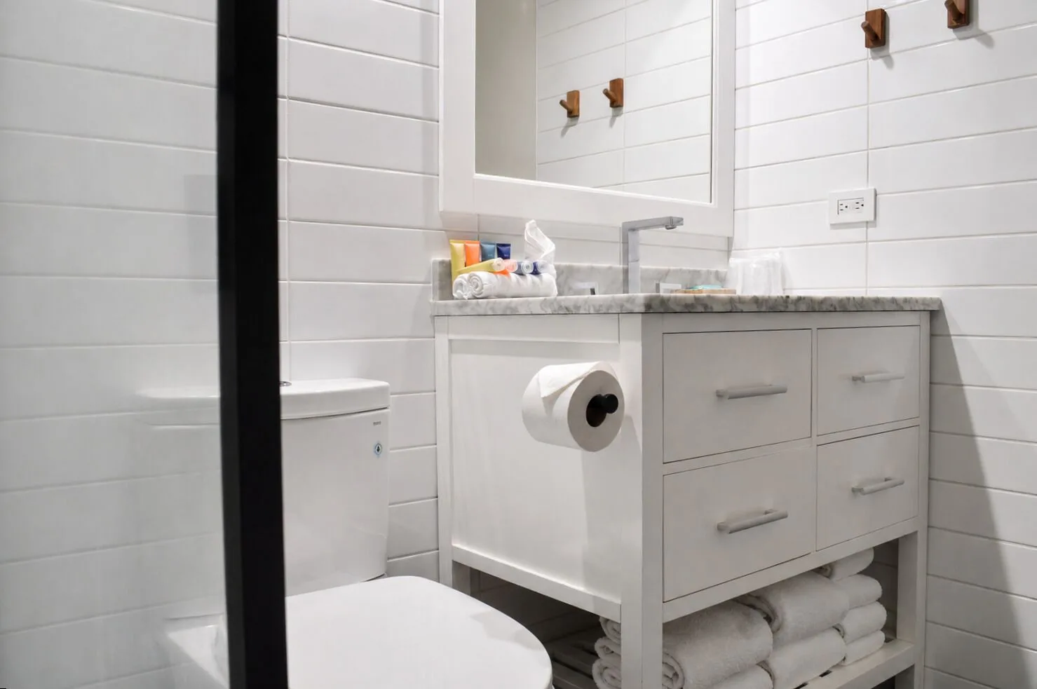 Premium Kalakaua Haus bathroom vanity and toilet beside glass shower at Hotel La Croix.