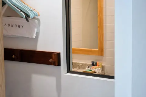 Closet hooks, hangers, and bathroom vanity view in a Premium Kalakaua Haus room at Hotel La Croix.