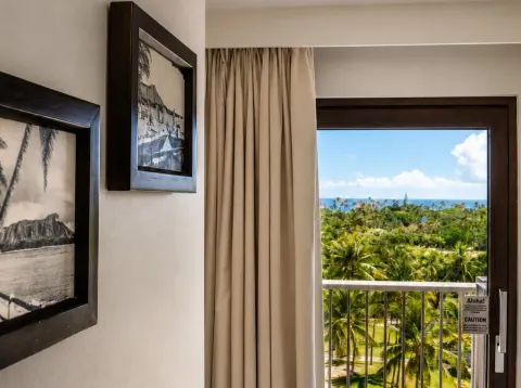 Premium Kalakaua Haus Oceanview room lanai doorway with palm and ocean view at Hotel La Croix.