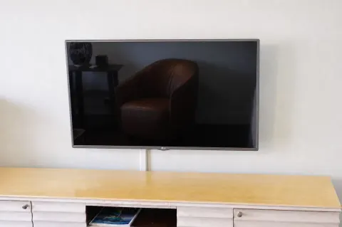 Flat-screen TV above a dresser in a Premium Kalakaua Haus room at Hotel La Croix.