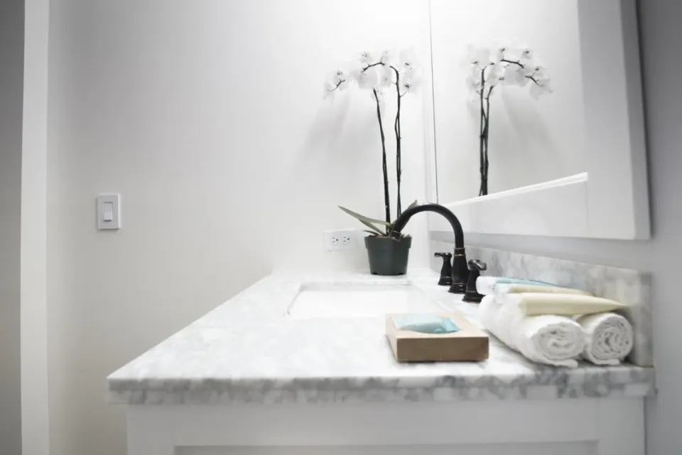 Bathroom vanity with marble counter, black faucet, towels, and orchid at Hotel La Croix.