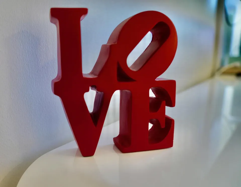 Red LOVE sculpture on a white surface in a Standard room at Hotel La Croix.
