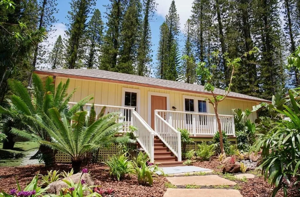 Exterior cottage-style building at Hotel Lanai with stairs, deck, and tropical landscaping.