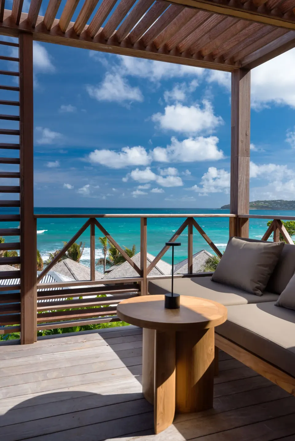 Covered balcony with sofa and ocean view at Hotel Manapany.