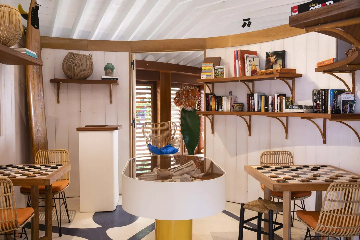 Game room with bookshelves, checkerboards and rattan chairs at Hotel Manapany.