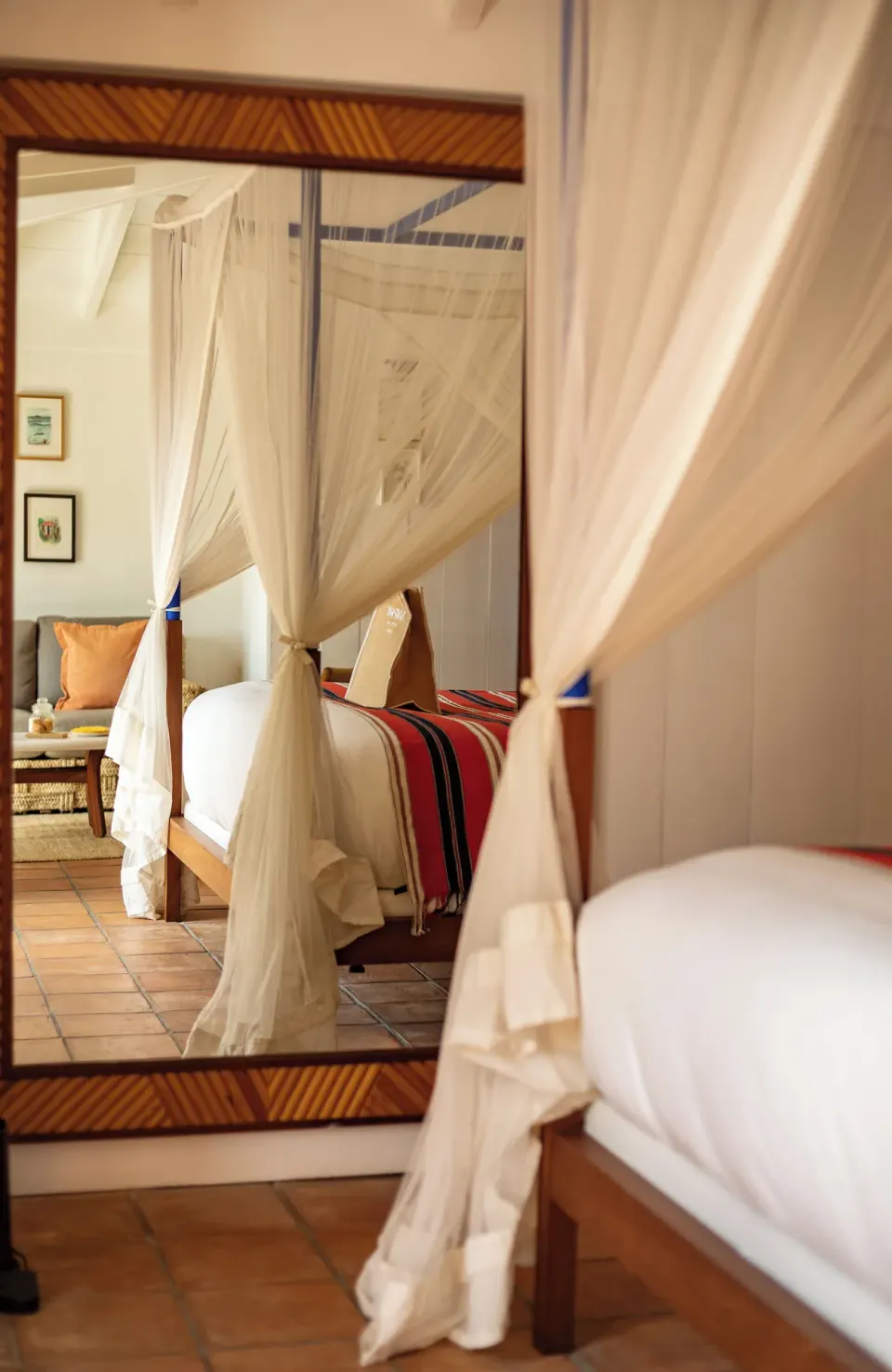 Guest room bed reflected in a framed mirror at Hotel Manapany.